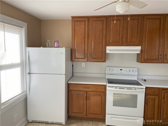 kitchen featuring under cabinet range hood, brown cabinets, white appliances, and light countertops