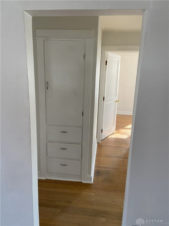 corridor featuring baseboards and hardwood / wood-style flooring