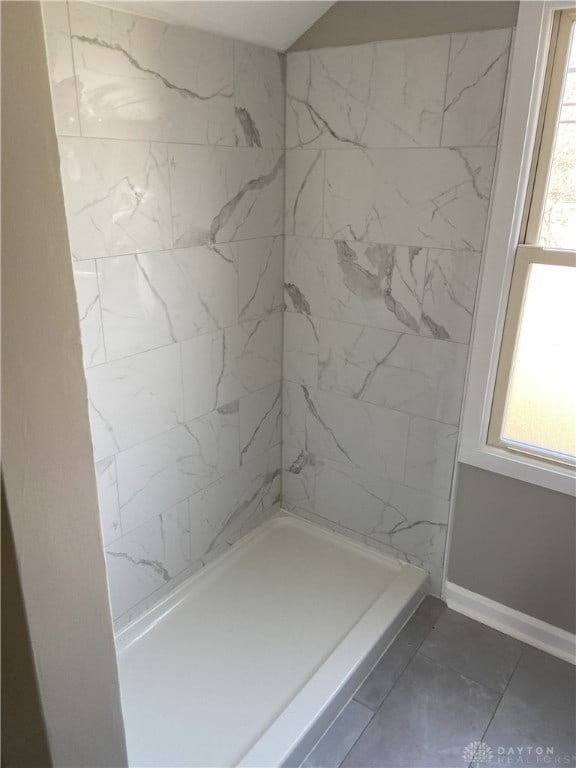 full bath with marble finish floor, a shower, baseboards, and a wealth of natural light