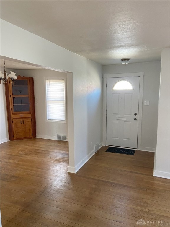 foyer entrance with baseboards, visible vents, an inviting chandelier, wood-type flooring, and a textured ceiling