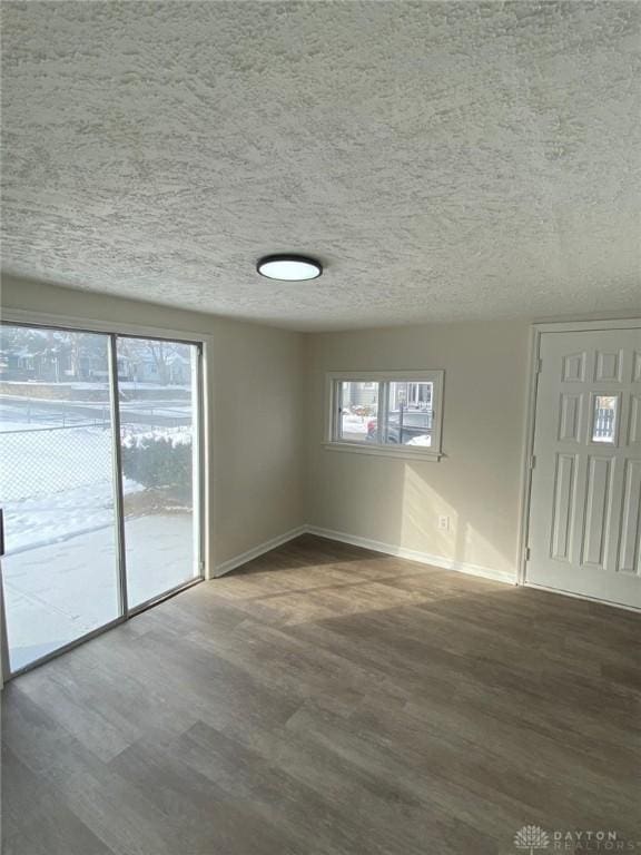 empty room featuring a textured ceiling, baseboards, and wood finished floors