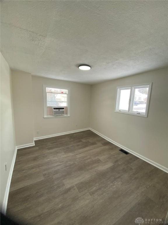 1297 Southlyn Dr, Dayton, OH 45409 - unfurnished room featuring a textured ceiling, dark wood finished floors, baseboards, and cooling unit