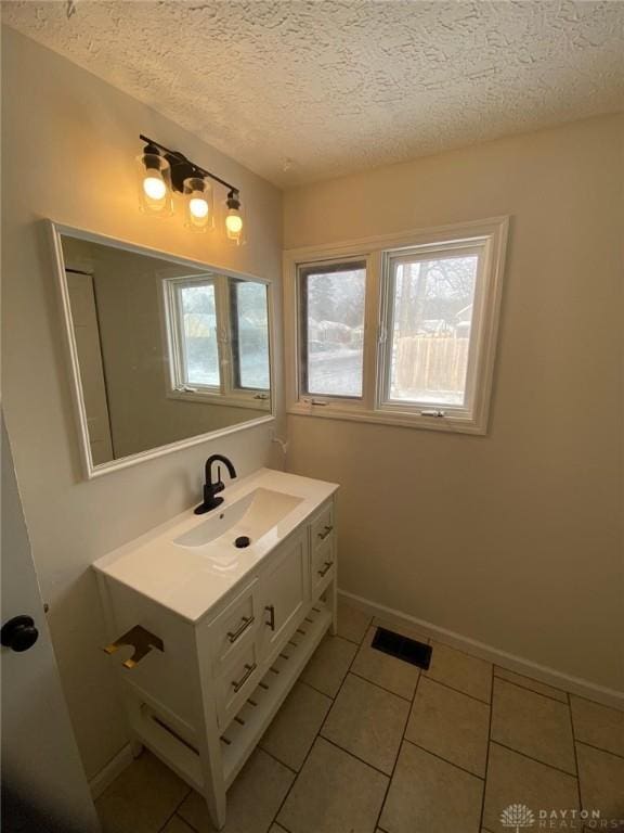 bathroom featuring visible vents, a textured ceiling, tile patterned flooring, baseboards, and vanity