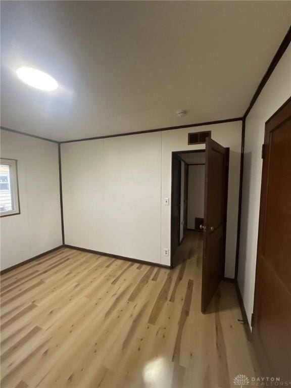 unfurnished room with visible vents, crown molding, and light wood finished floors