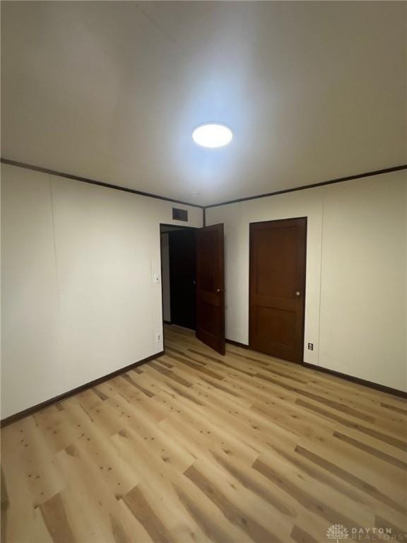 unfurnished bedroom with visible vents, light wood-style flooring, and baseboards