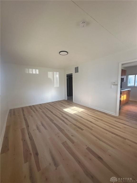 empty room featuring visible vents, light wood-style flooring, and baseboards