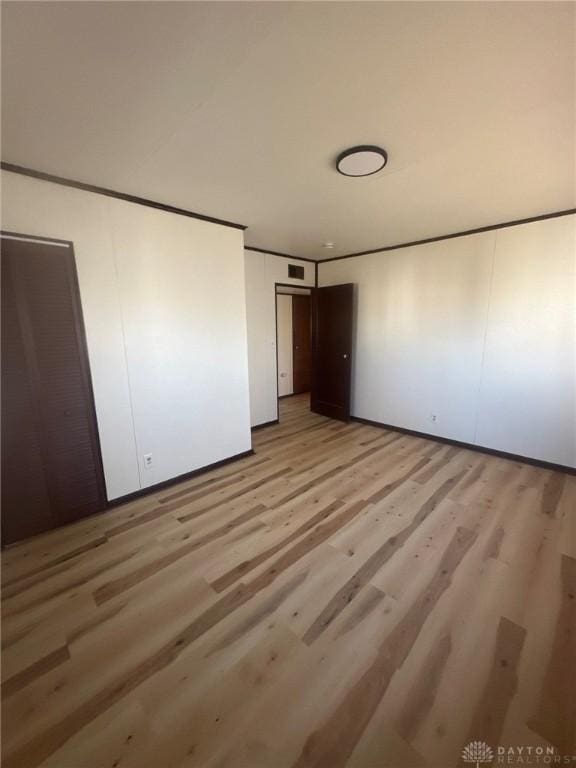 unfurnished bedroom with visible vents, light wood-type flooring, and ornamental molding