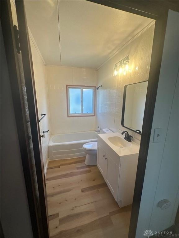 full bath with toilet, wood finished floors, tile walls,  shower combination, and vanity