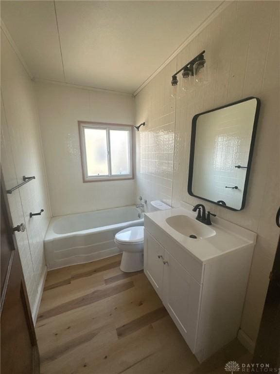 full bathroom featuring shower / washtub combination, toilet, ornamental molding, wood finished floors, and vanity