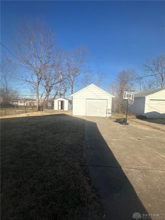 view of side of property featuring a detached garage, an outdoor structure, and driveway