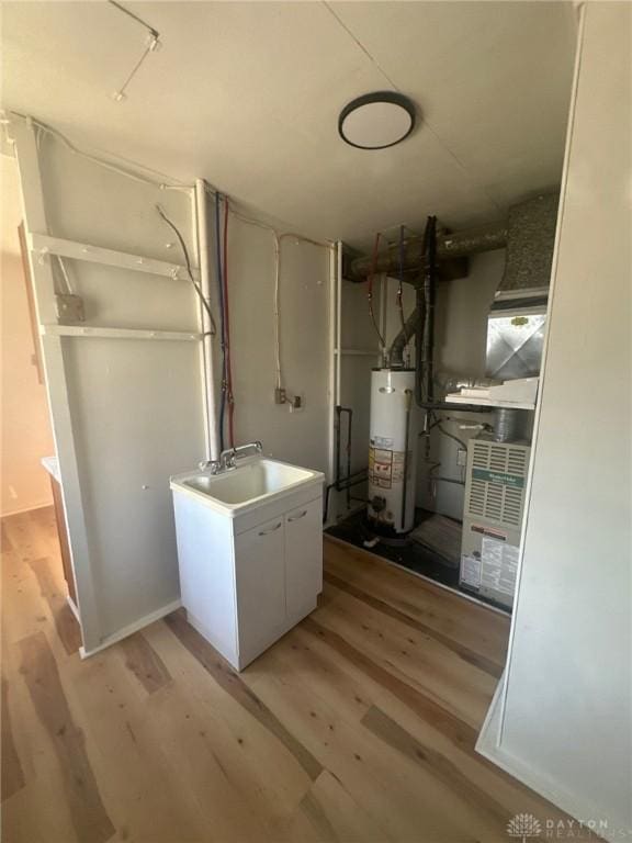 utility room with gas water heater and a sink