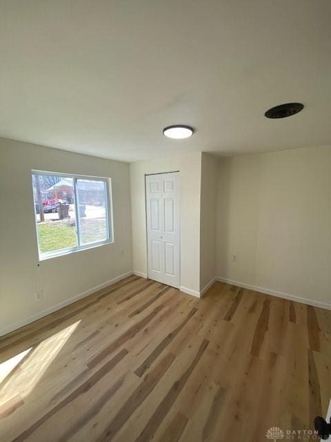 unfurnished bedroom featuring a closet, baseboards, and wood finished floors