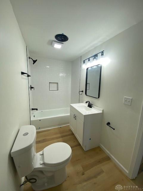 bathroom with baseboards, toilet, bathing tub / shower combination, wood finished floors, and vanity