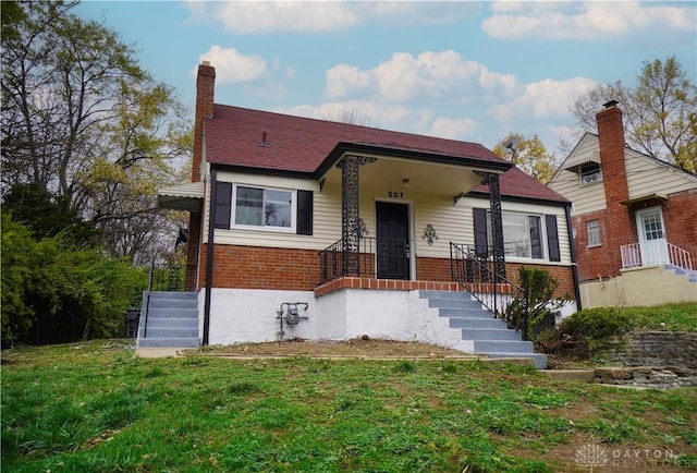 view of front facade featuring brick siding, a chimney, and a front lawn