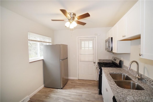 kitchen with light stone counters, plenty of natural light, appliances with stainless steel finishes, and a sink