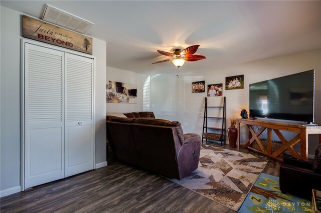 living area featuring visible vents, baseboards, dark wood-type flooring, and a ceiling fan