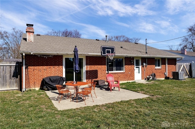 back of house featuring fence, brick siding, central AC, a patio area, and a lawn