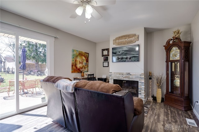 living area featuring visible vents, a ceiling fan, wood finished floors, and a fireplace