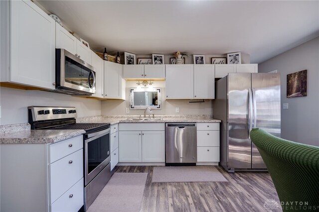 kitchen featuring a sink, wood finished floors, appliances with stainless steel finishes, and white cabinets