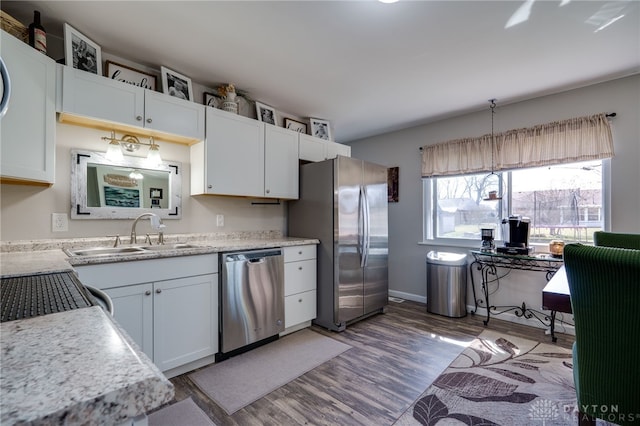 kitchen with light countertops, stainless steel appliances, light wood-style floors, white cabinetry, and a sink