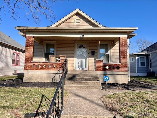 bungalow with covered porch and brick siding