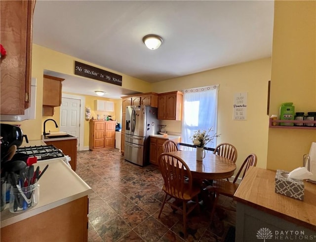 kitchen with white gas range, a sink, light countertops, and stainless steel fridge with ice dispenser