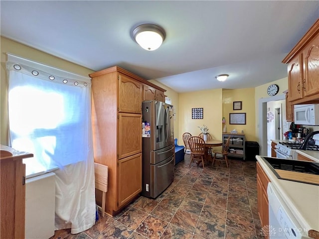 kitchen with stone finish flooring, white appliances, brown cabinets, and light countertops