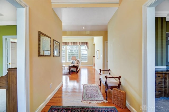 corridor featuring crown molding, wood finished floors, and baseboards