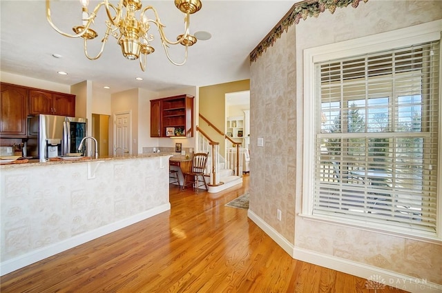 kitchen featuring a notable chandelier, open shelves, stainless steel fridge, light wood-style floors, and baseboards