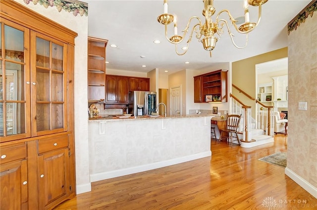 kitchen featuring light wood finished floors, stainless steel fridge with ice dispenser, a chandelier, a peninsula, and open shelves