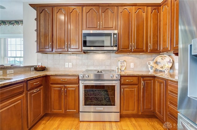 kitchen featuring light stone counters, brown cabinets, and appliances with stainless steel finishes