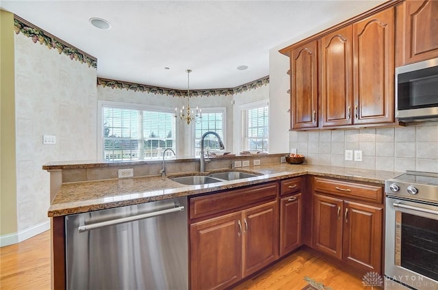 kitchen featuring a sink, stainless steel appliances, light wood-style floors, and brown cabinetry