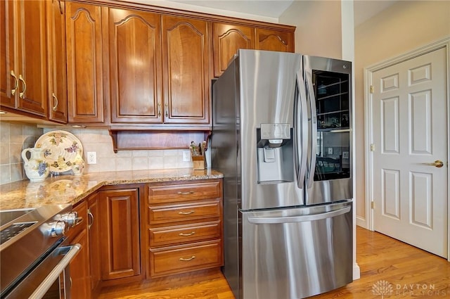 kitchen featuring brown cabinets, stainless steel appliances, and light stone countertops