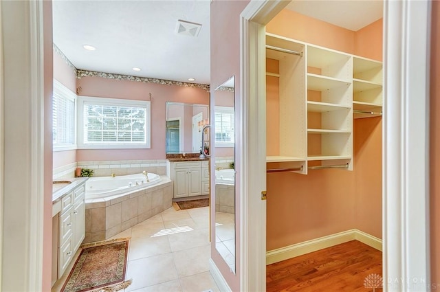 bathroom featuring tile patterned floors, visible vents, a garden tub, and vanity