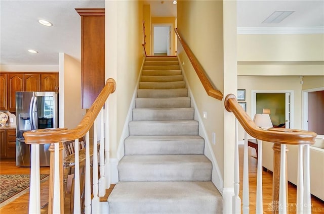 stairway with visible vents, crown molding, baseboards, recessed lighting, and wood finished floors