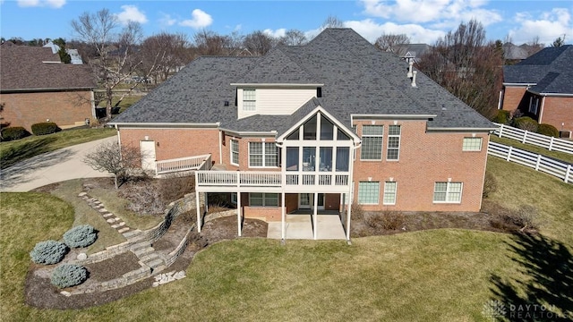 back of house featuring fence, a yard, a shingled roof, brick siding, and a patio area