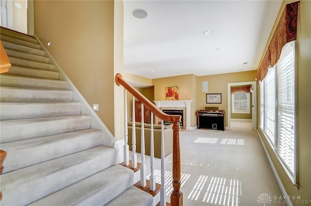 stairway featuring recessed lighting, baseboards, carpet, and a fireplace