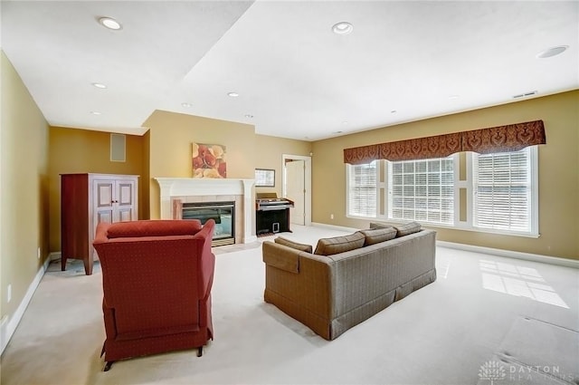 living area with visible vents, a glass covered fireplace, recessed lighting, baseboards, and light colored carpet