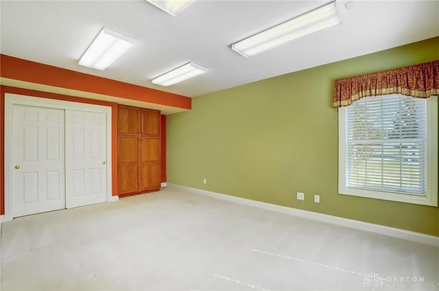 unfurnished bedroom featuring light carpet, a closet, and baseboards