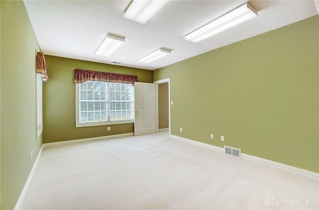 empty room featuring visible vents, light colored carpet, and baseboards