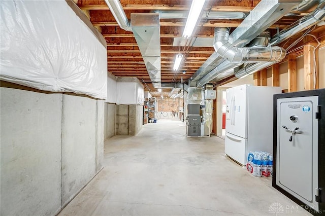 unfinished basement with heating unit and white refrigerator with ice dispenser