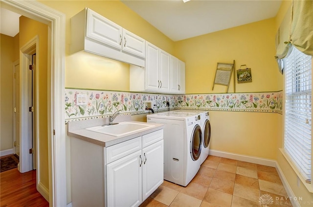 washroom featuring cabinet space, independent washer and dryer, baseboards, and a sink