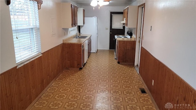 kitchen with a wainscoted wall, light floors, white appliances, and visible vents