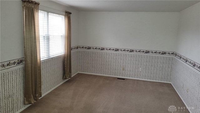 carpeted empty room with a wainscoted wall, wallpapered walls, and baseboards