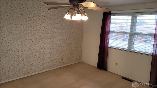 empty room featuring visible vents, light carpet, wallpapered walls, baseboards, and ceiling fan