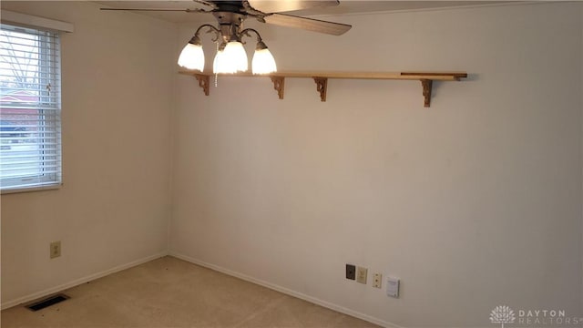 unfurnished room featuring visible vents, light colored carpet, a healthy amount of sunlight, and ceiling fan