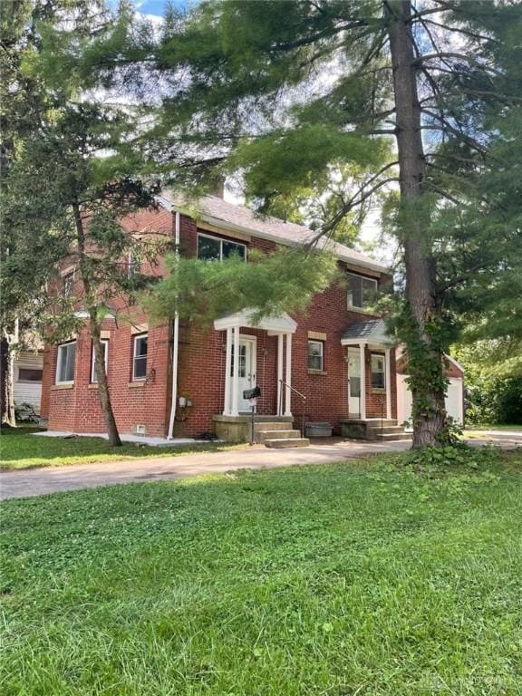 view of front of house with a front yard, brick siding, and a chimney