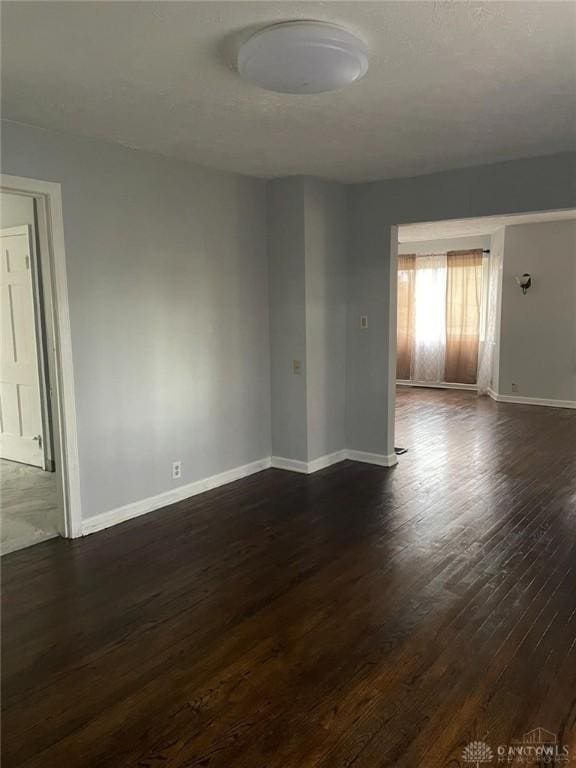 empty room featuring baseboards and dark wood-style flooring