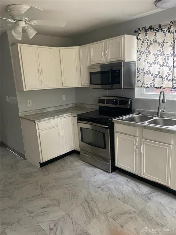 kitchen with a ceiling fan, a sink, stainless steel appliances, white cabinets, and marble finish floor