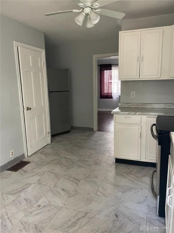 kitchen with baseboards, ceiling fan, stainless steel electric range oven, light countertops, and freestanding refrigerator